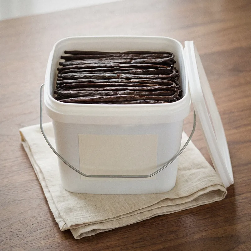 Offener Lebensmitteleimer voller ganzer Bourbon-Gourmet-Vanilleschoten, leeres Eigenmarken-Etikett