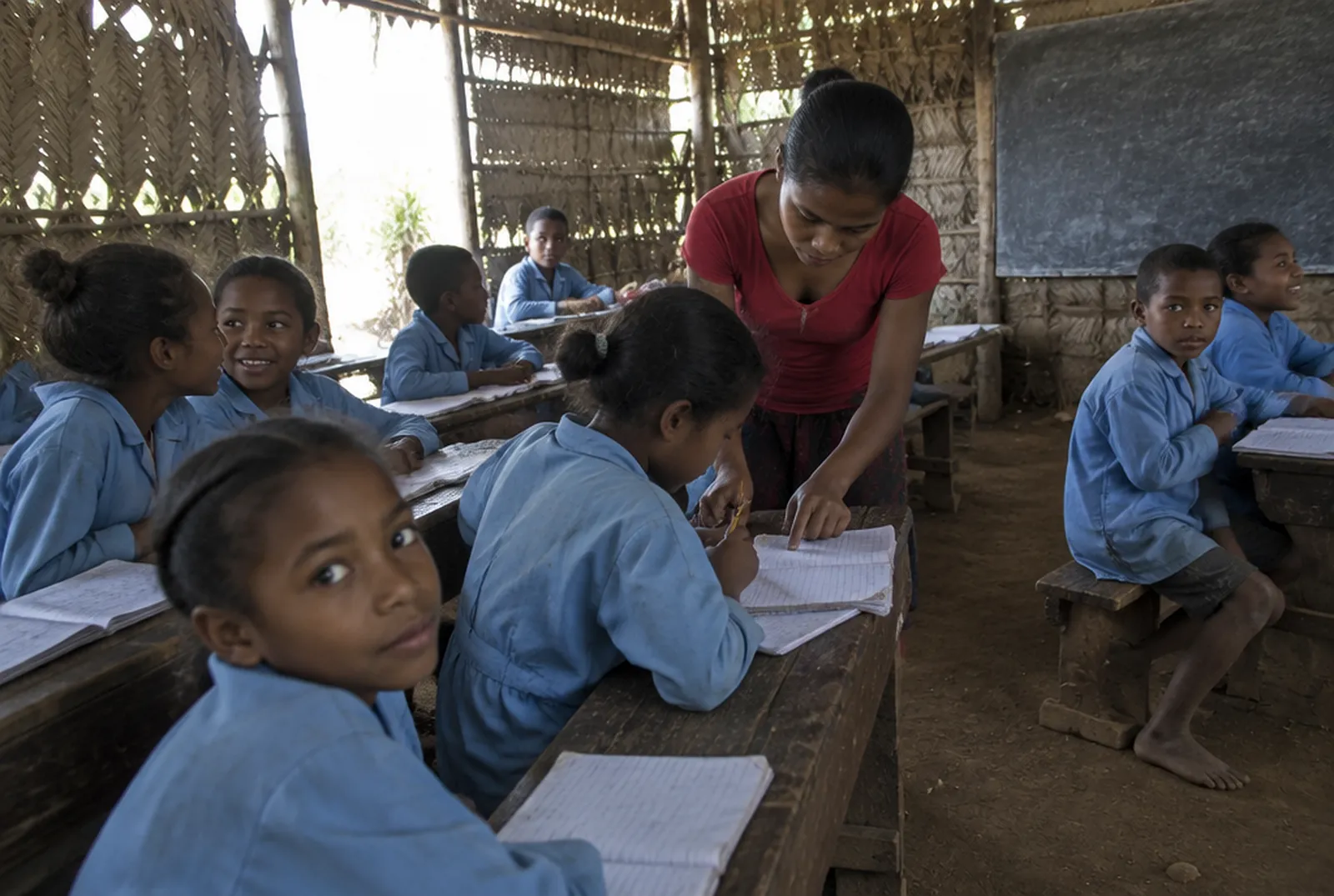 A teacher helping a pupil in a village classroom near Maroantsetra A teacher helping a pupil in a village classroom near Maroantsetra