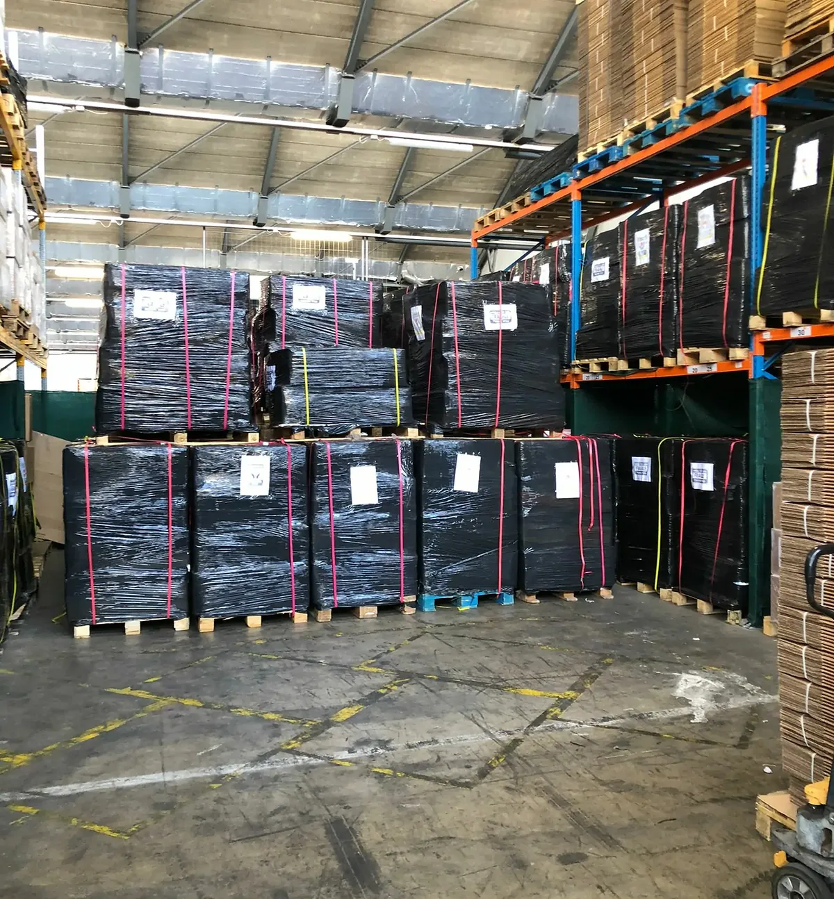 Palettes filmées et étiquetées stockées sur des racks dans l'entrepôt Vanilla Fair